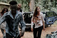 一辆失事的汽车旁，有一群逼真的僵尸在森林环境中