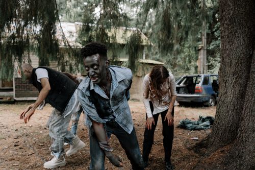 Free Zombies wandering in a forest, creating a spooky Halloween scene. Stock Photo