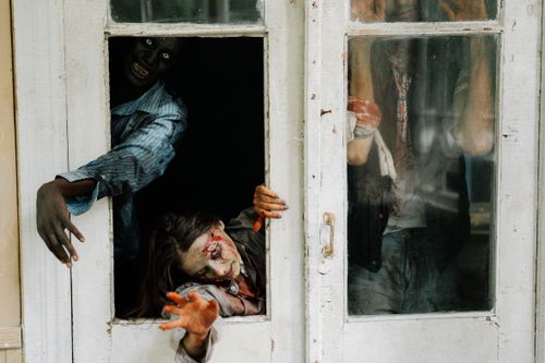 Free Zombies emerge menacingly from an abandoned house, perfect for horror themes. Stock Photo