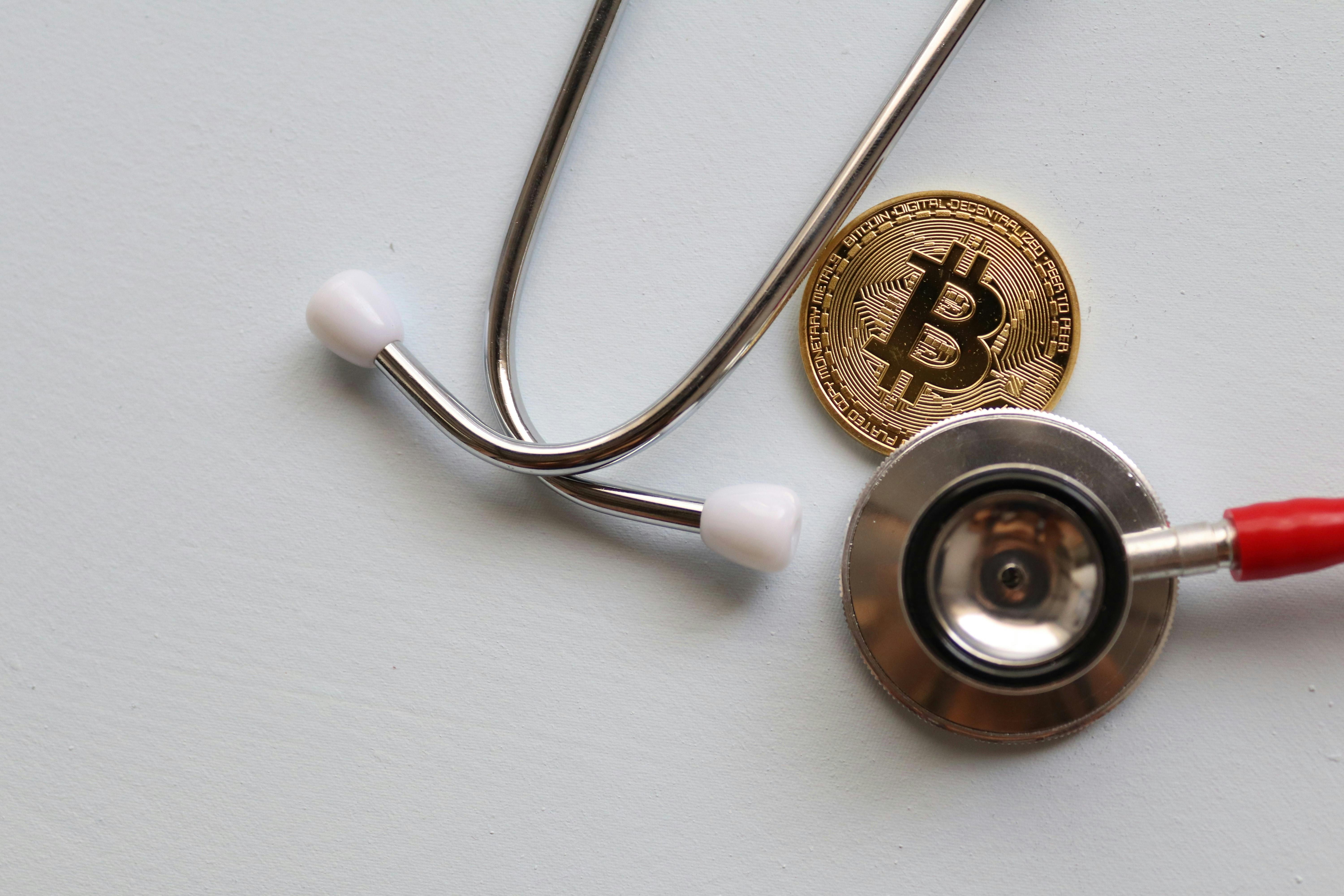 stethoscope and bitcoin on white surface