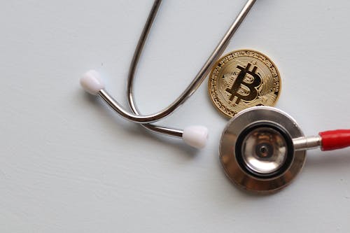 Free Stethoscope and Bitcoin on White Surface Stock Photo