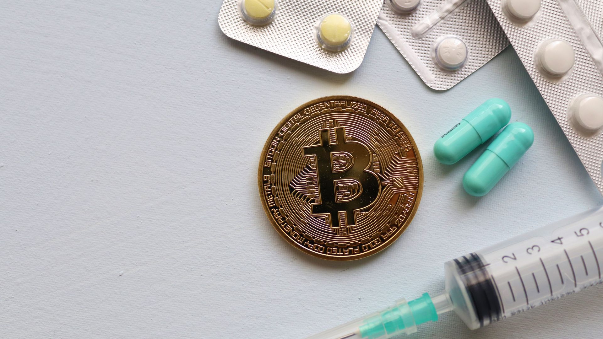 Modafinil Online Pharmacy: Your Ultimate Guide Image of a Bitcoin coin surrounded by pills and a syringe, symbolizing healthcare and finance.
