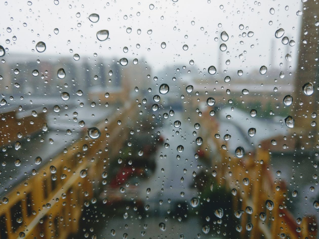 Raindrops on a window with a blurred street behind