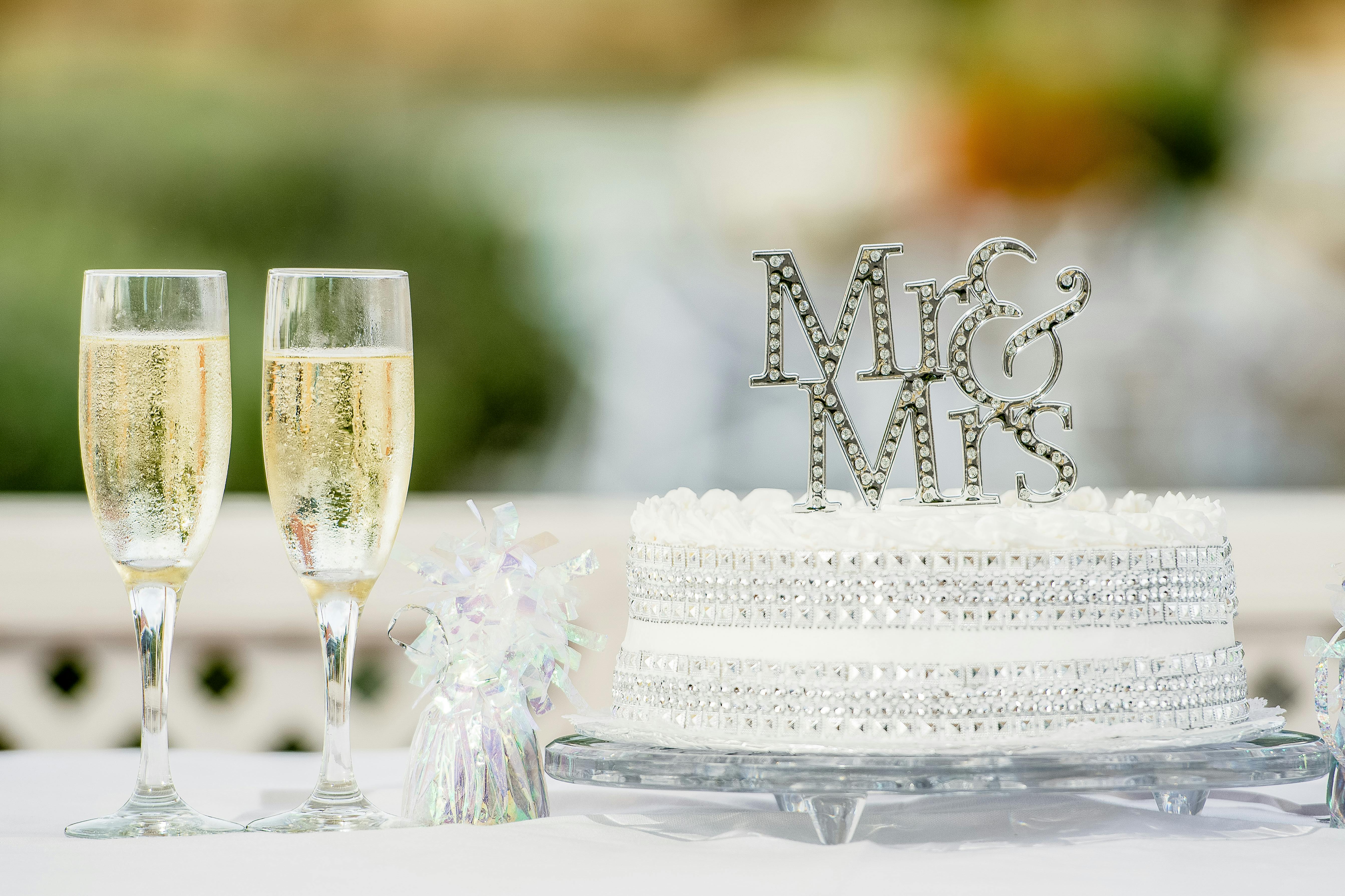 A stylish wedding scene featuring a cake with 'Mr & Mrs' topper and champagne flutes.