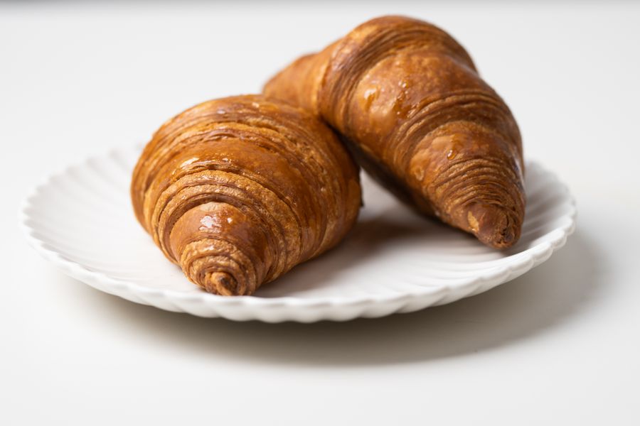 Close-up of two freshly baked croissants on a white plate, perfect for breakfast.