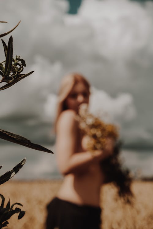Topless woman with flowers in field