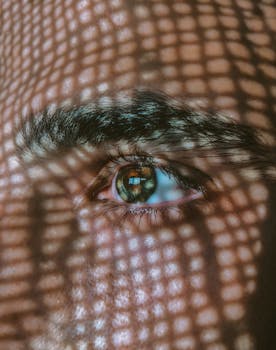 A detailed close-up of an eye with intricate geometric shadows cast across it.