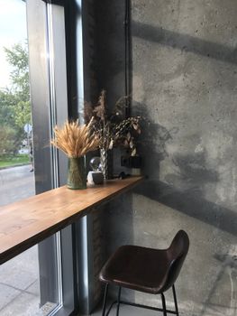 Warm rustic cafe nook with decorative plants by a large window.
