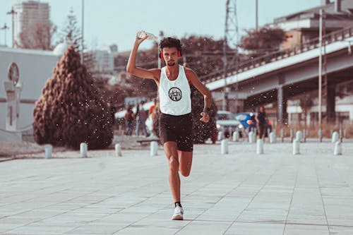 Young male athlete pouring water while running in park