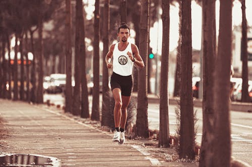 Free Fit concentrated sportsman running along palms Stock Photo