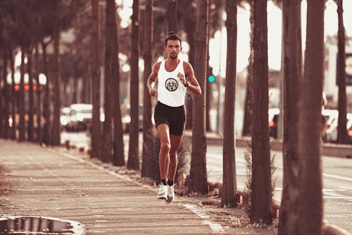 Fit concentrated sportsman running along palms