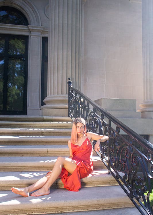 Free Woman in Red Dress Barefoot Sitting on Staircase Stock Photo
