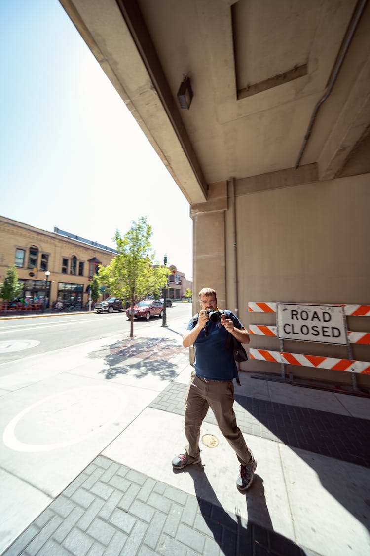 Man Taking Photo In Reflection On Street