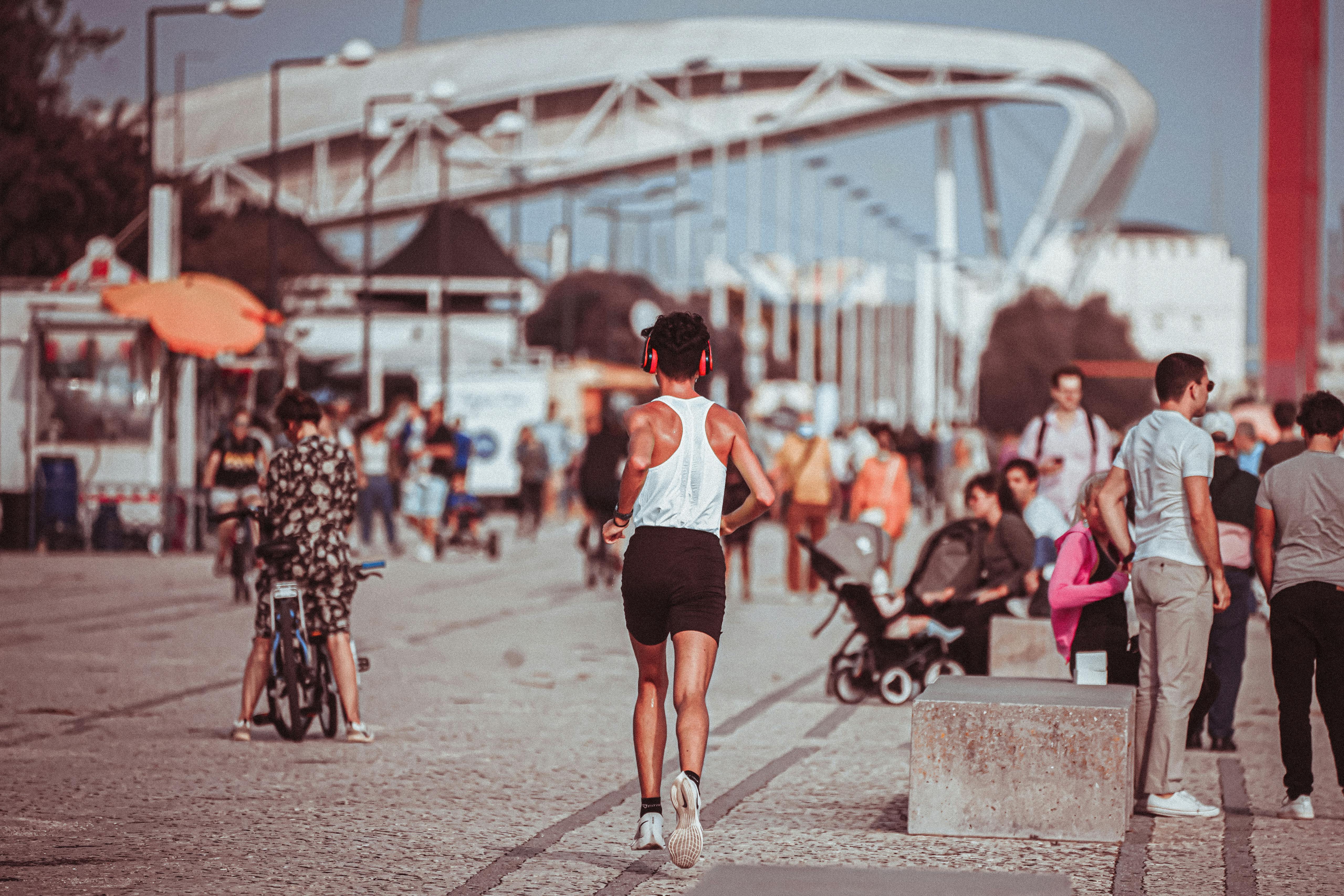 active man in headphones running in crowded park