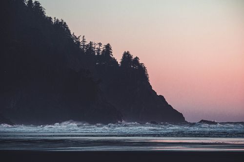 Free Stunning silhouette of rocky coastline during a pink-hued sunset at Neskowin Beach, Oregon. Stock Photo