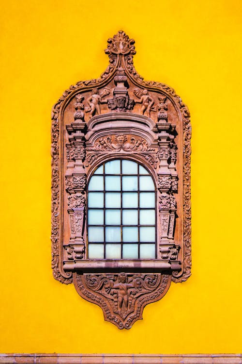 Exterior detail of ancient Capilla de Aranzazu chapel with carved ornamental window on bright yellow wall in Spanish colonial style located in San Luis Potosi