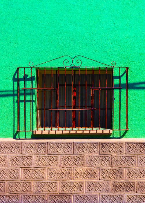 Free Detail of aged green building with small aged wooden window with metal decorative bars on sunny day Stock Photo