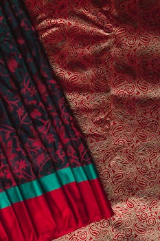 Close-up of an elegant red and black saree with intricate gold patterns, showcasing traditional Indian textile design.