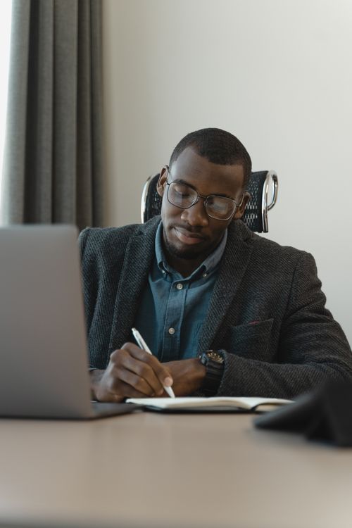 Free Professional man sitting at a desk writing notes in his office. Stock Photo