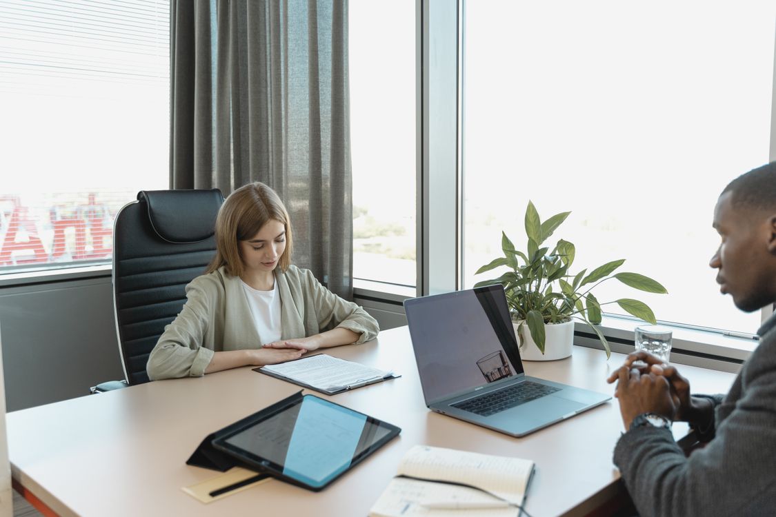 Free A diverse job interview scenario in a modern office setting with a laptop and documents on the table. Stock Photo