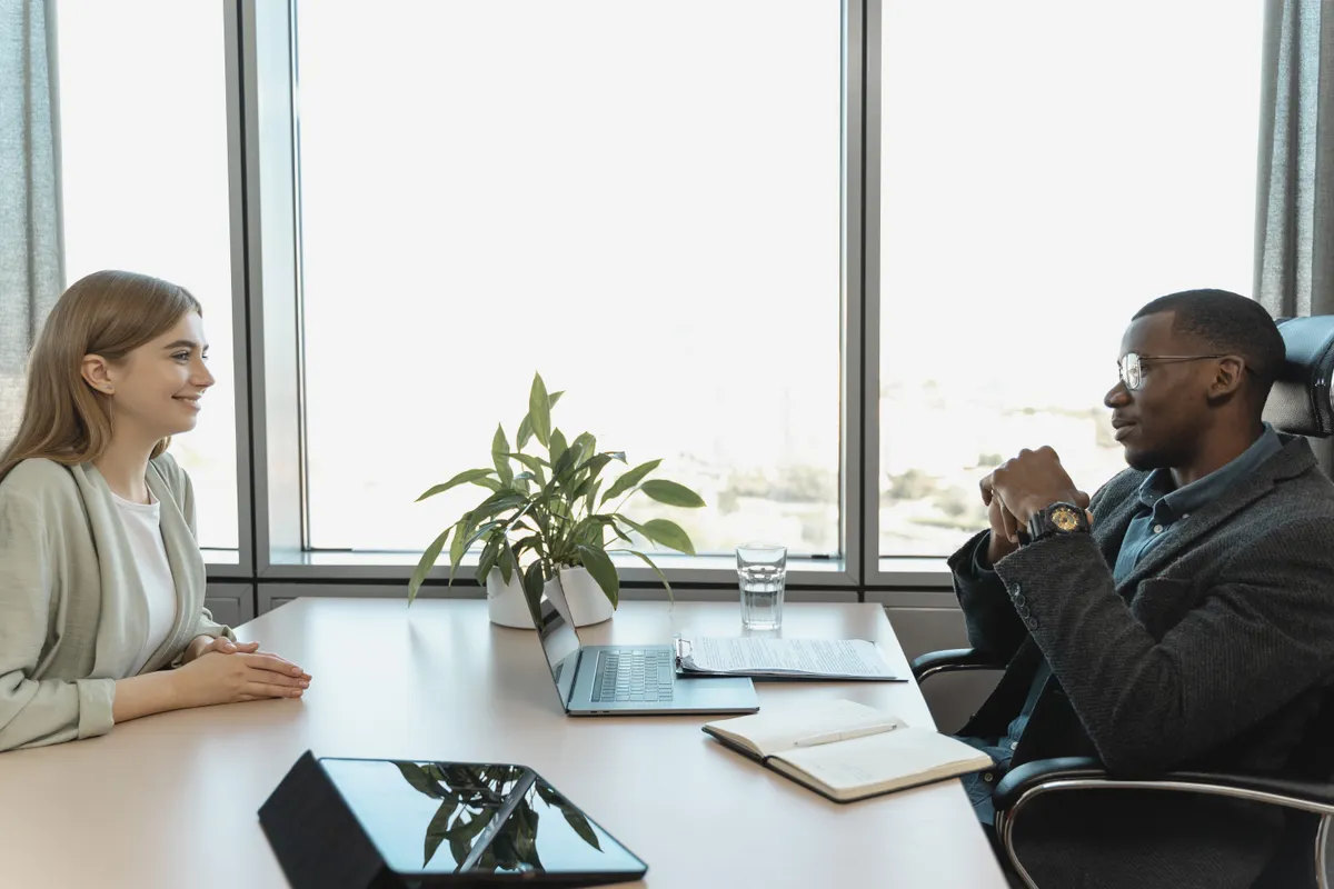 Perempuan profesional dalam suasana wawancara kantor membicarakan rekomendasi karir di meja modern