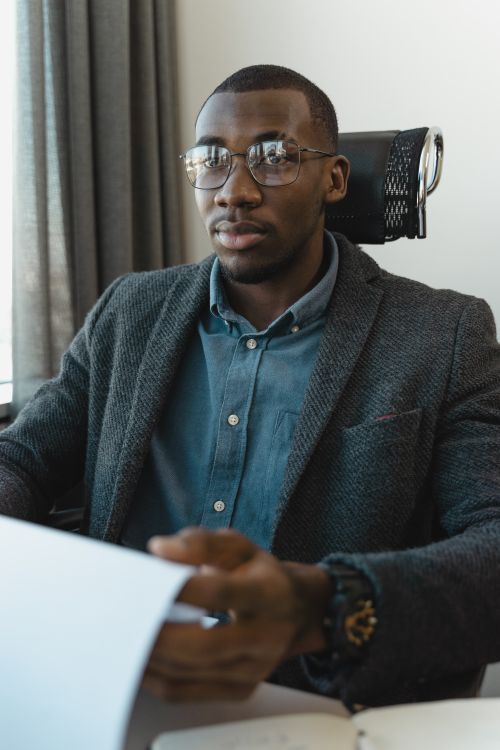 Free Professional young businessman in corporate attire with eyeglasses, focused on work at his desk. Stock Photo