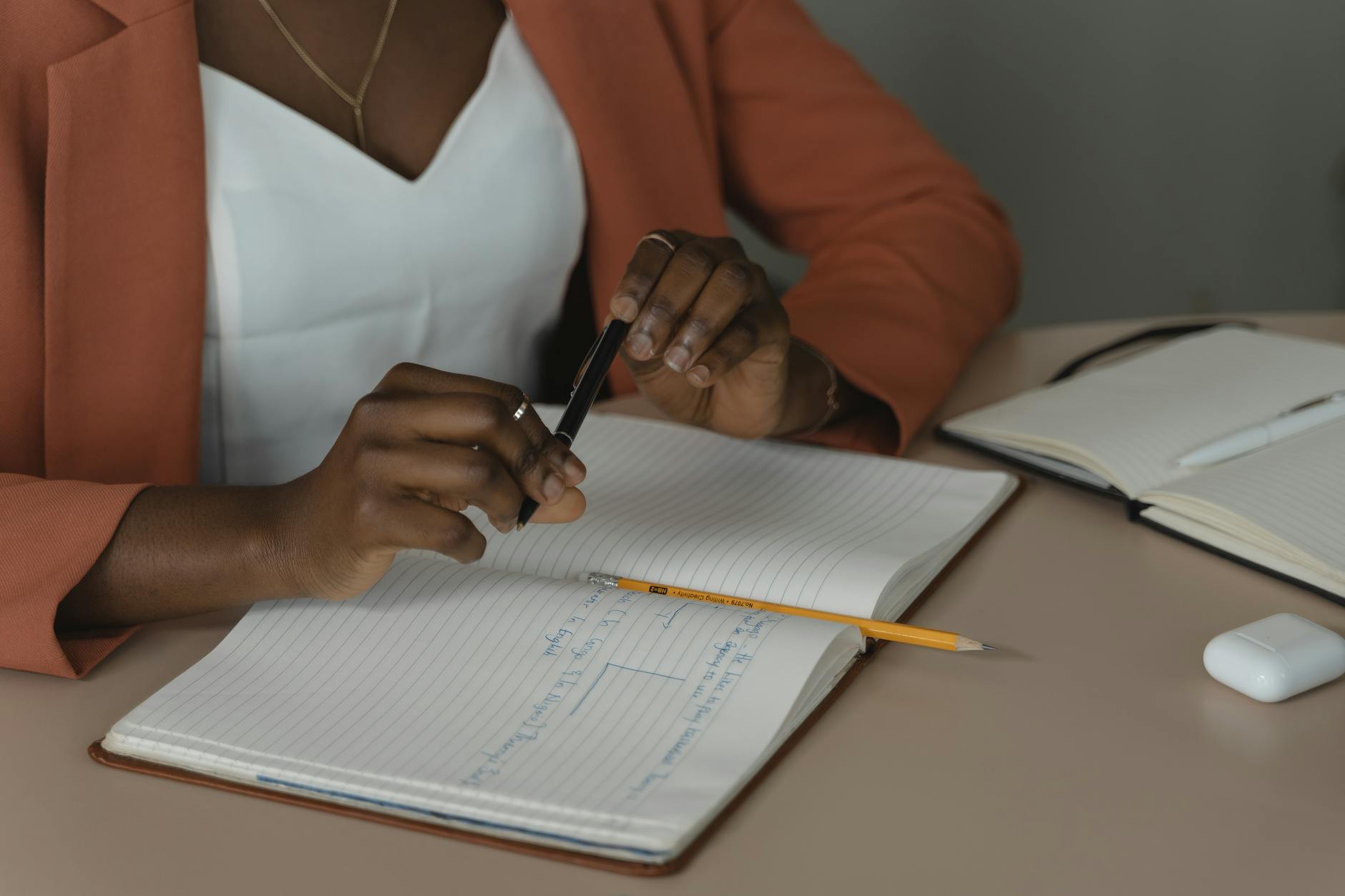 Woman Sitting by a Desk with a Notebook and a Pen