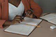 Woman Sitting by a Desk with a Notebook and a Pen