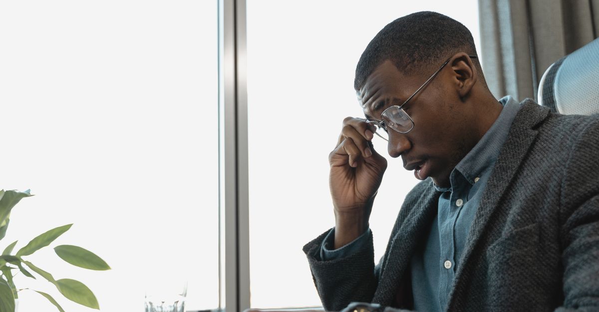 exhausted professional sitting at desk with hands on head, dramatic lighting