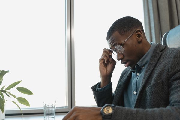 Person experiencing eye strain while wearing glasses at desk