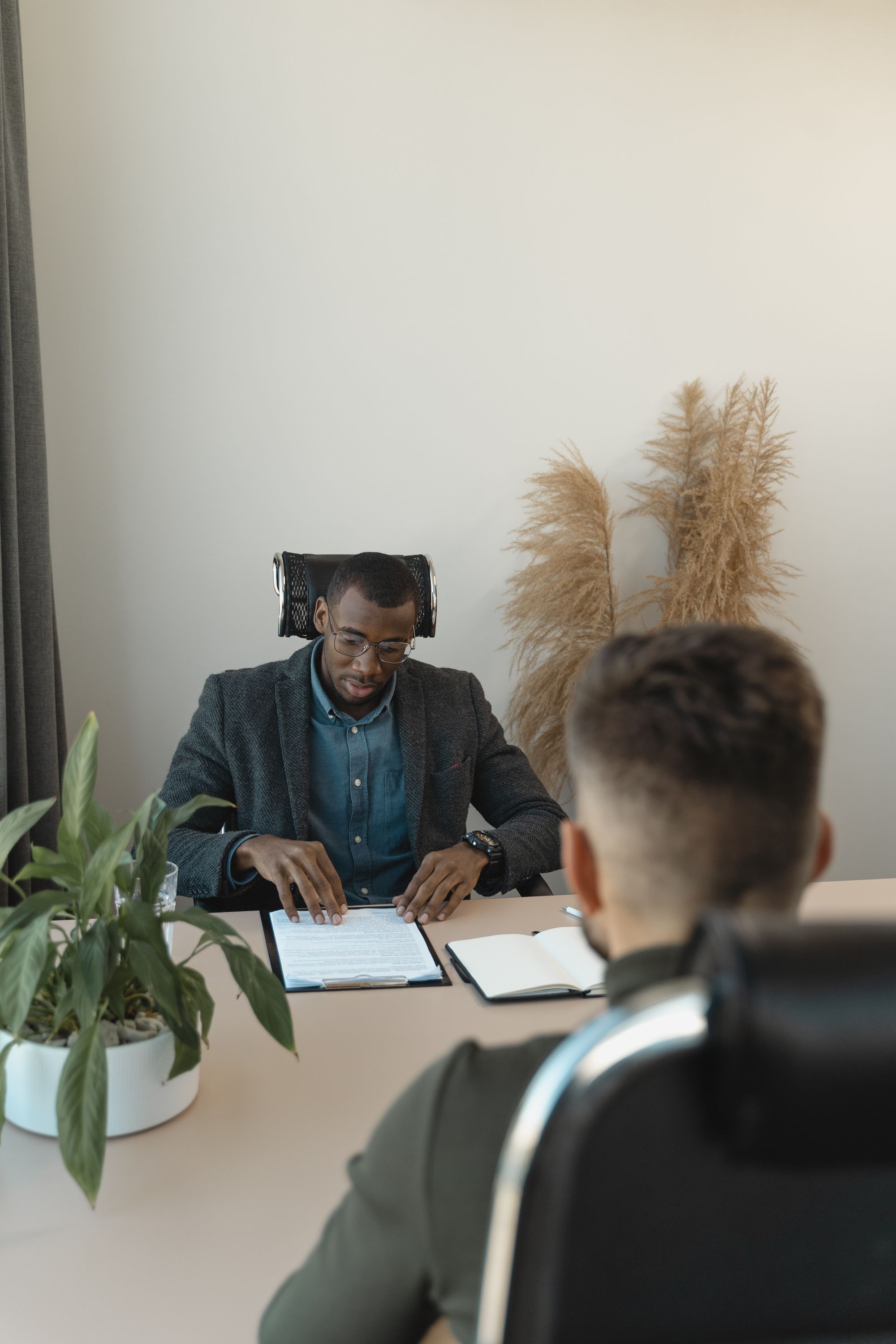 Two people in a job interview at a desk in an office with green plants