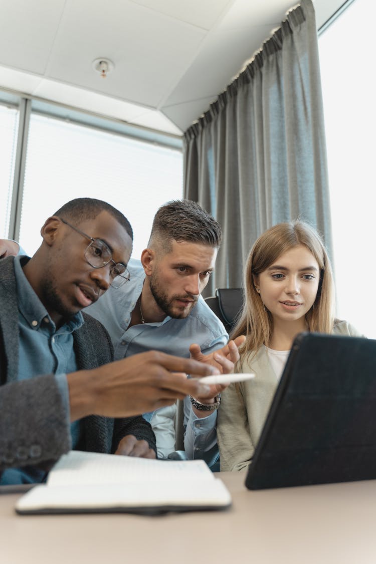 Employees Brainstorming While Looking At The Screen Of A Tablet