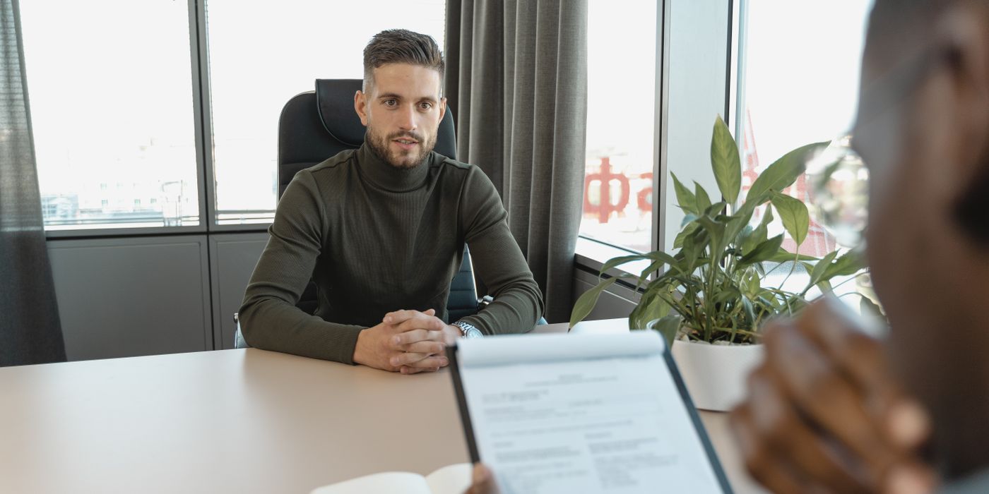 Professional man in turtleneck at office desk during an interview.