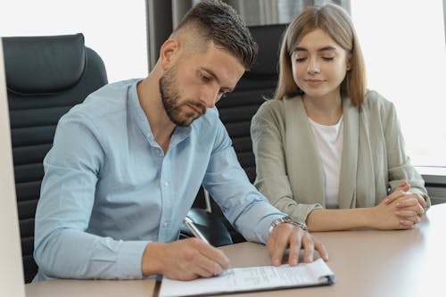 Man in Blue Dress Shirt Signing a Paper