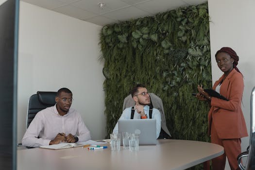 A diverse team of professionals engaging in a strategic office meeting with green plants decor.