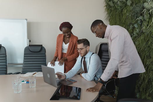 Diverse team discussing project ideas in modern workplace setting with laptops.