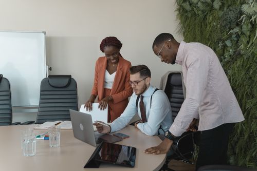 Free Diverse team discussing project ideas in modern workplace setting with laptops. Stock Photo