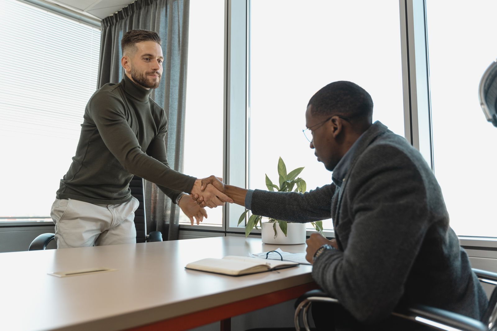Entretien d'embauche dans un bureau : poignée de main entre un recruteur et un candidat.