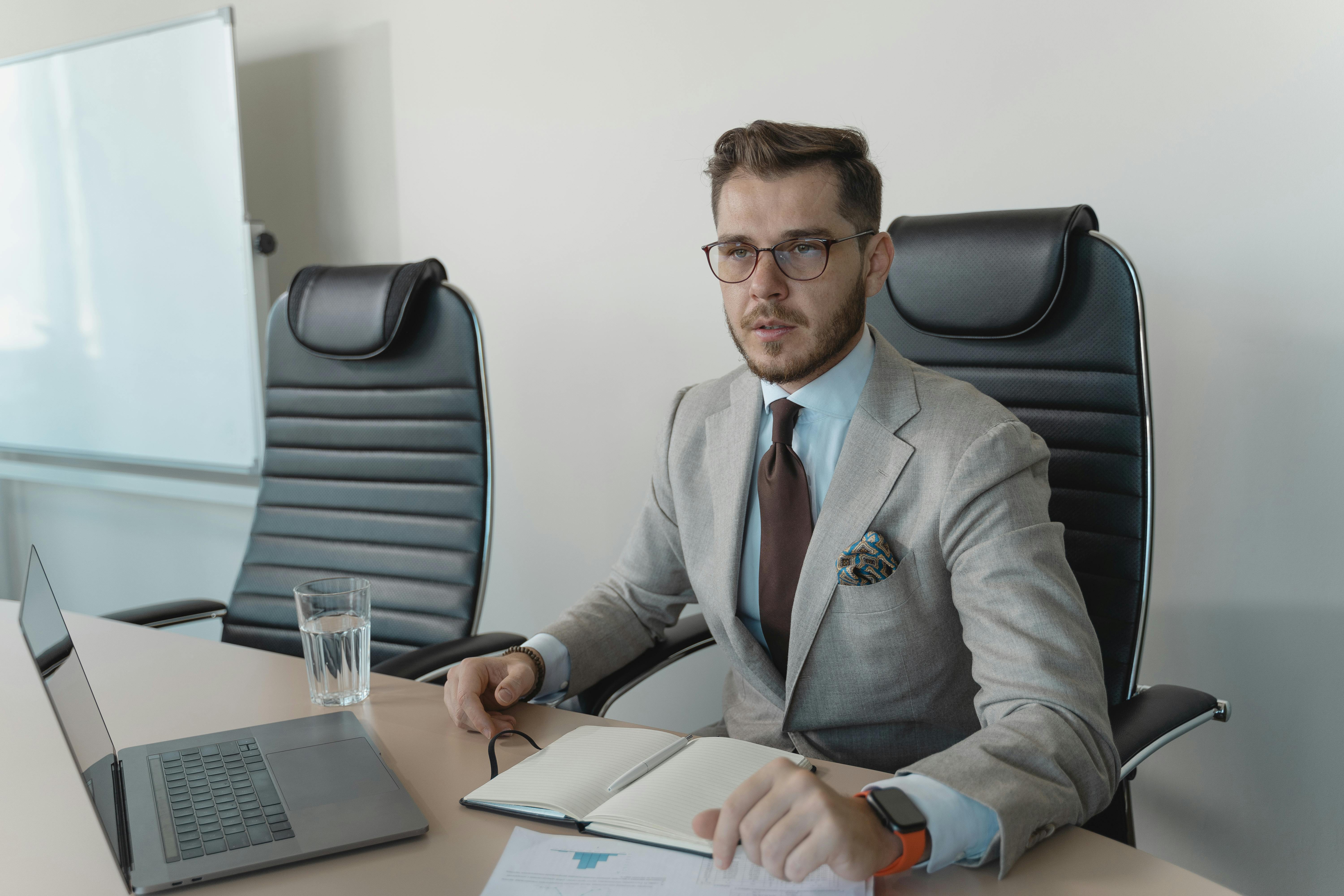 A Man Wearing a Business Suit and Eyeglasses Sitting