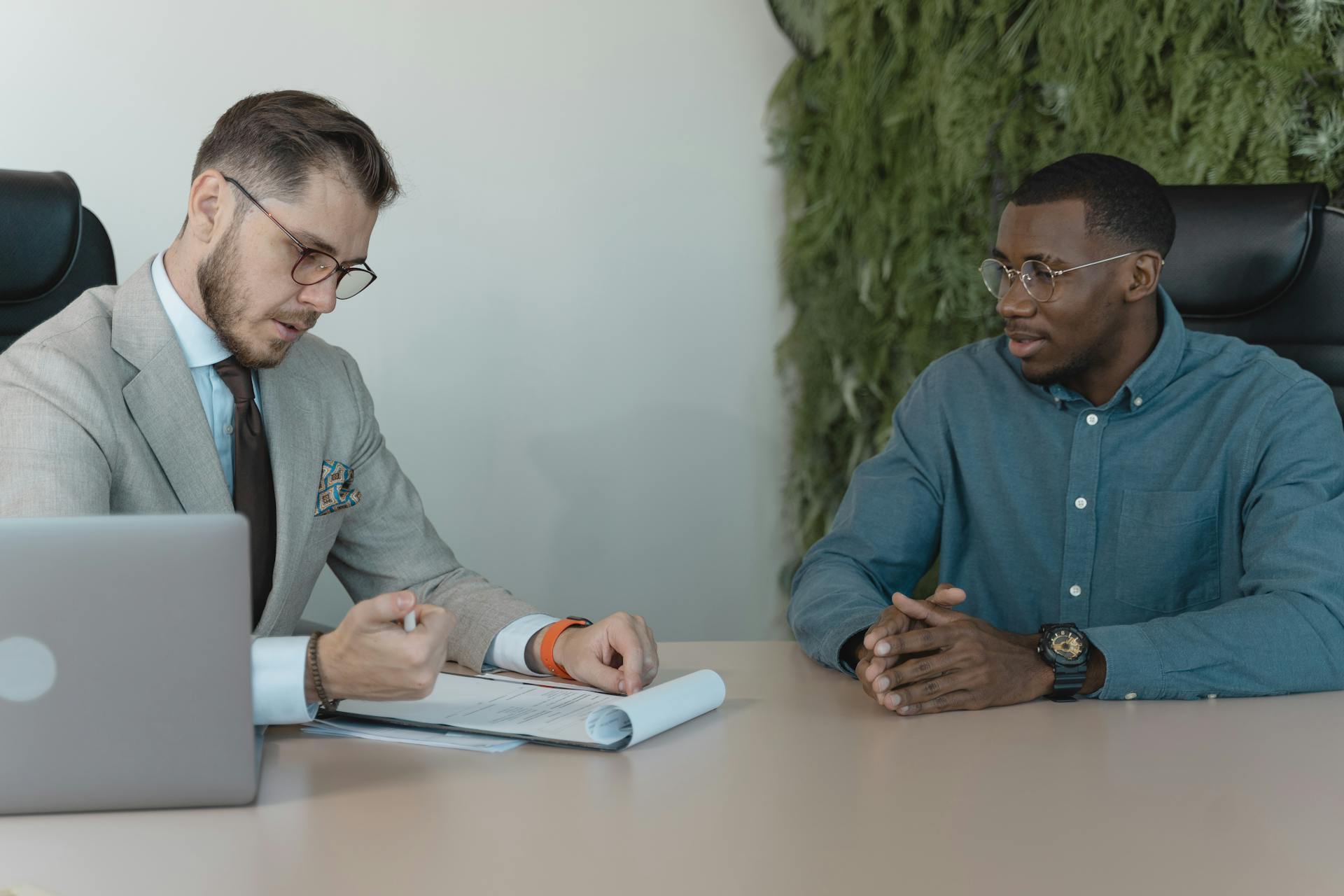 A professional job interview between two men in a modern office environment.