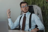 Bearded Man Sitting on an Office Chair Holding a Pen while Listening