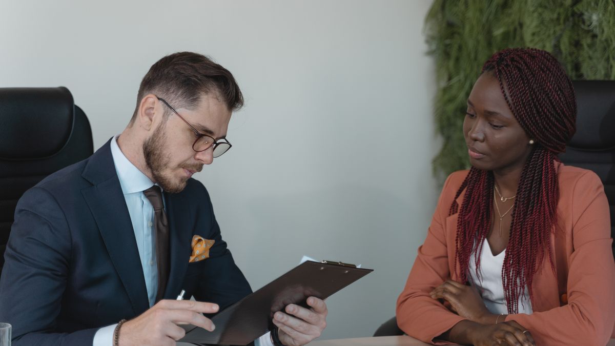 Recrutador analisando o currículo de uma candidata durante entrevista de emprego