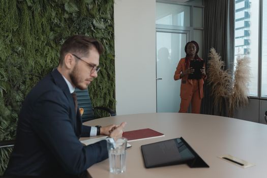 Business meeting between a man and a woman in a modern office with greenery wall.