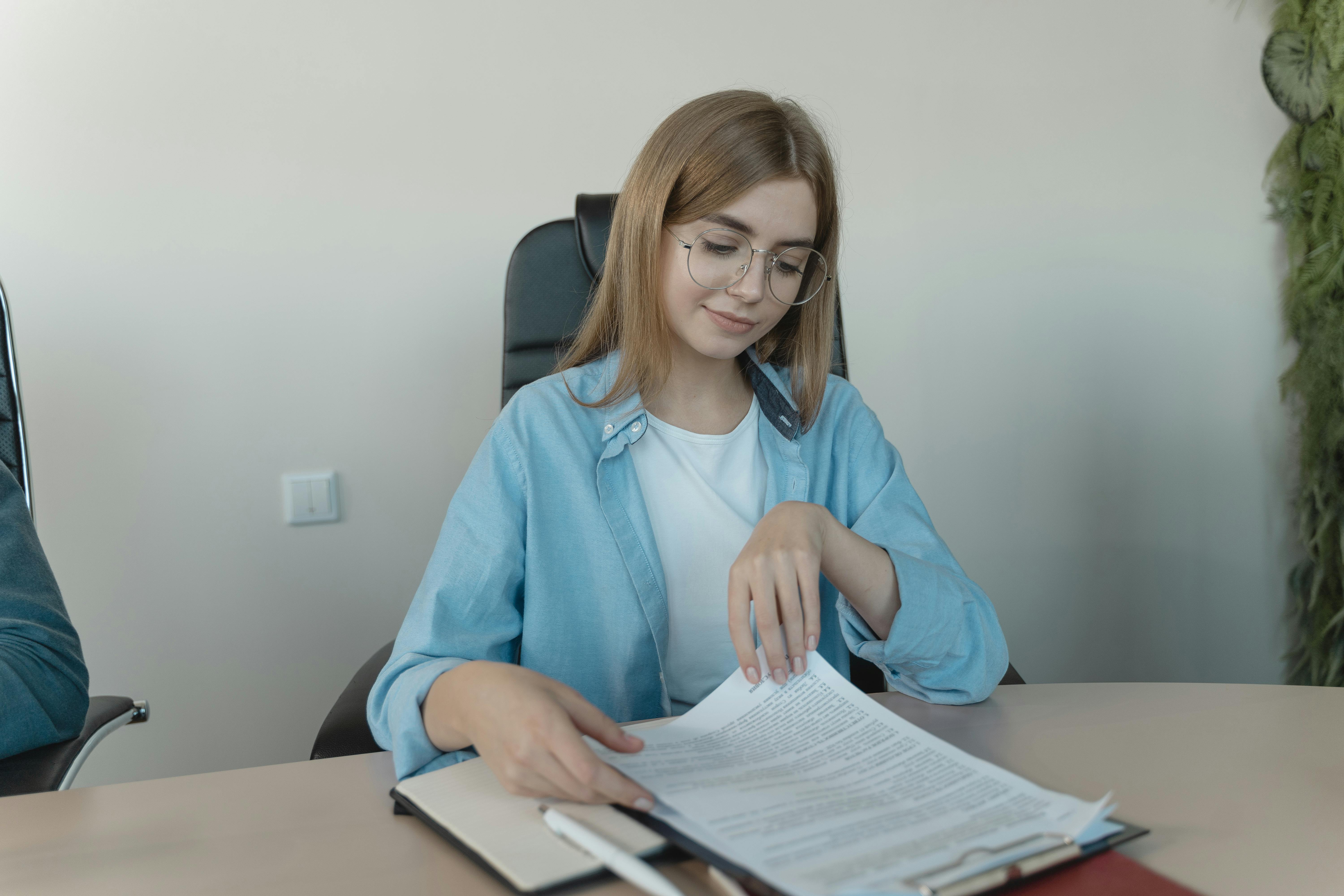 woman sitting on an office chair while reading the document on a clipboard