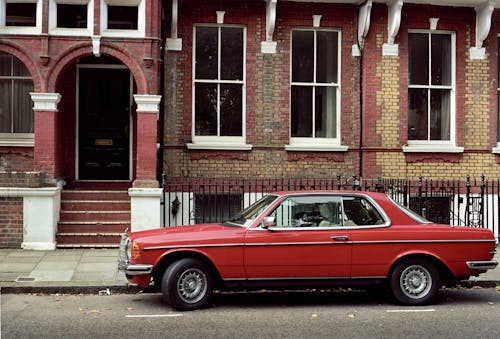 Red Sedan Parked Near the Brick Building