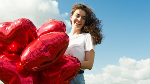 Happy Woman in White T-shirt Holding Red Balloons
