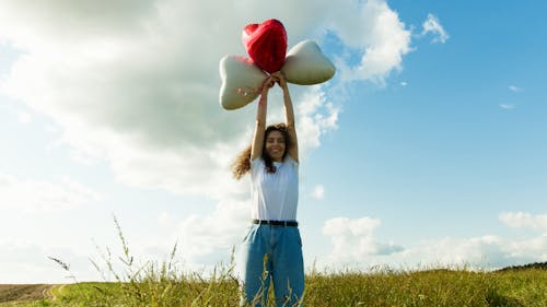 A Woman in a White Shirt Holding Balloons