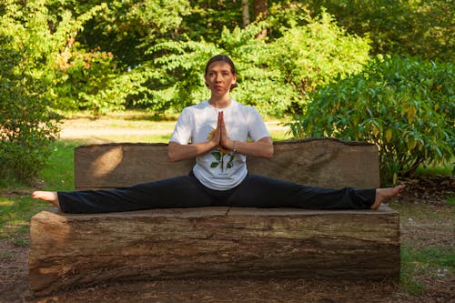Woman in White Crew Neck T-shirt and Black Pants Sitting on Brown Wooden Log during