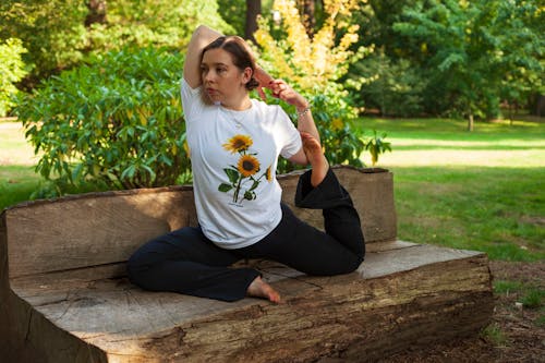Woman in White Crew Neck T-shirt and Black Pants Sitting on Brown Concrete Bench during