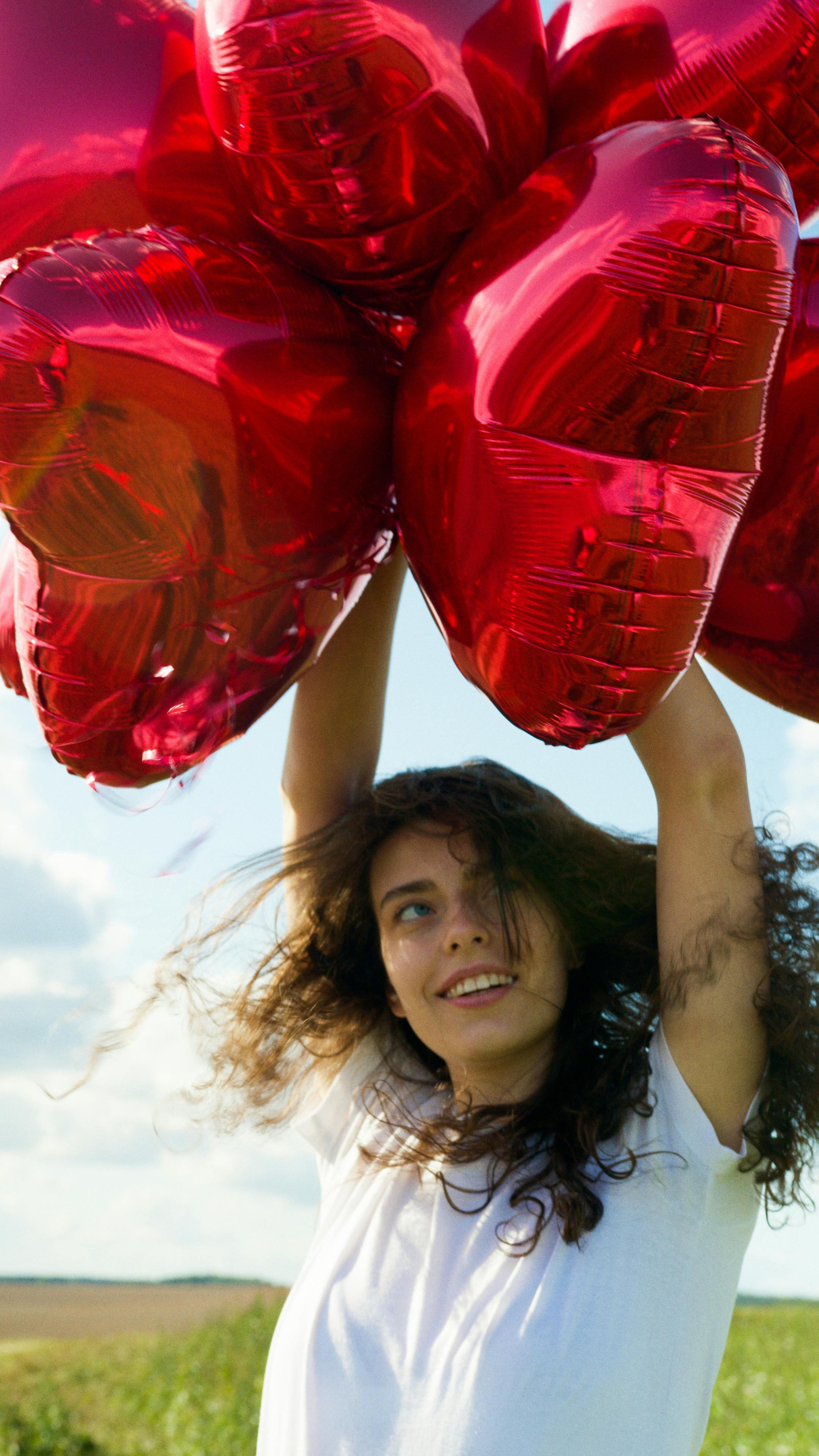 a woman holding red balloons